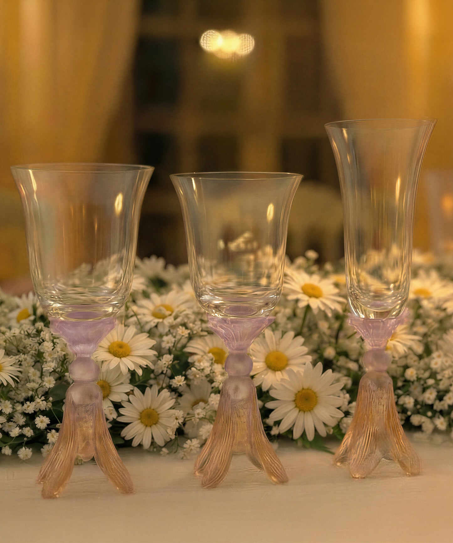Deux verres à eau en or d'abeille de la marque Daum Intérieur, élégants et décoratifs, posés sur une surface en verre.