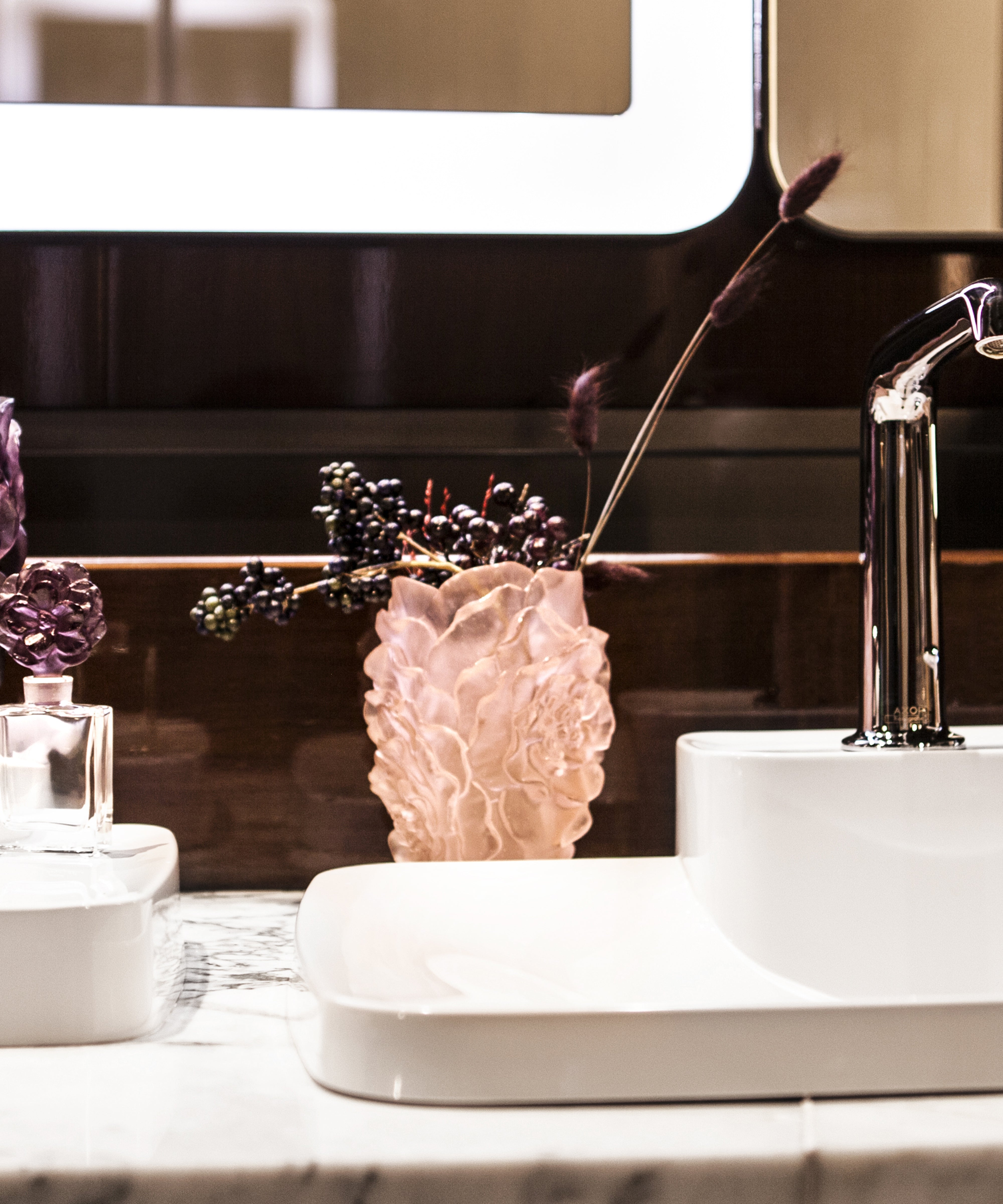 Vase petit modèle Camélia Daum en verre rose avec motif floral délicat, posé sur une surface claire.