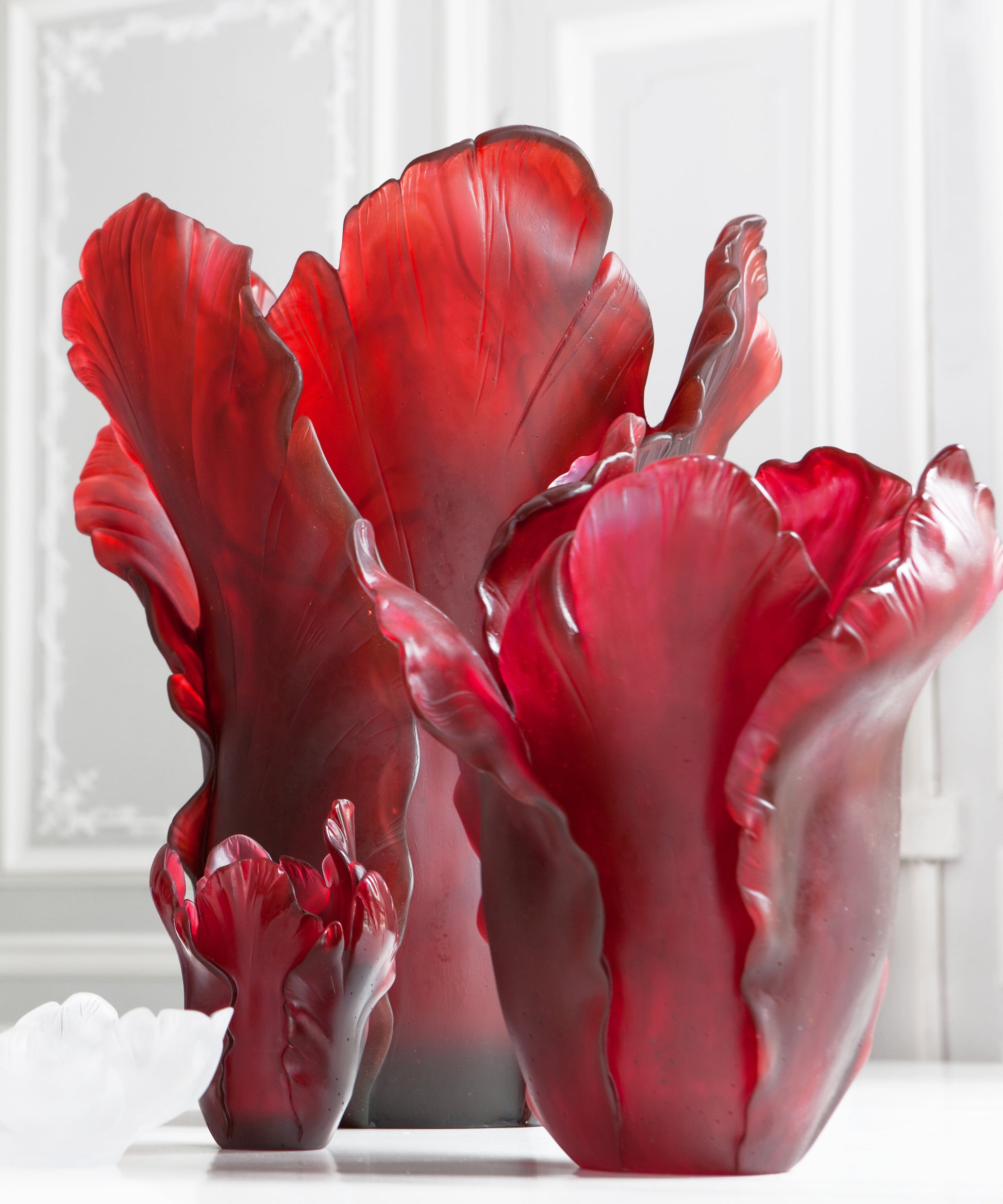 Vase Tulipe rouge en verre Daum avec forme élégante et finition brillante, posé sur une surface blanche.